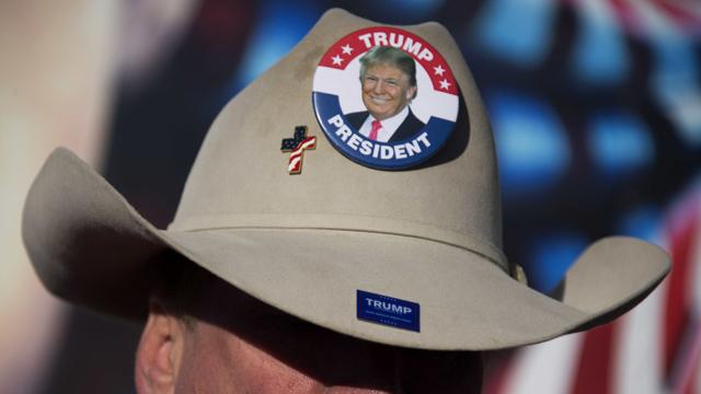 Homem com chapéu de cowboy e broches de campanha de Trump