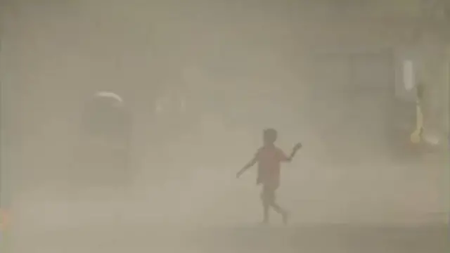 প্রচণ্ড ধুলার মাঝে রাস্তা দিয়ে হেঁটে যাচ্ছে এক শিশু