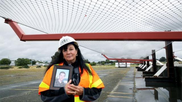 Dayna Whitmer holds a portrait of her son under one of the Golden Gate Bridge safety nets