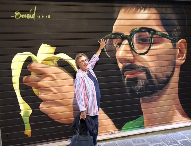 anciana frente a mural de arte urbano