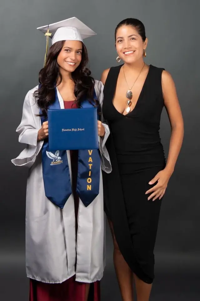 Giulianna Carriel y su tía Gia Calero. Una chica con traje de graduación de secundaria junto a una mujer con vestido negro y el pelo tomado.