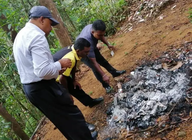 පුළුස්සන ලද දෑ නිරීක්ෂණය කරන නිලධාරීන්