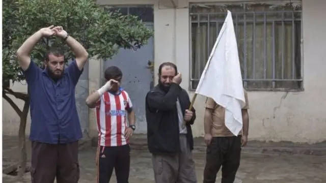 Abanyagihugu mu munezero bafise ibendera ryera mu gihe abasirikare bariko barasaka inzu yabo mu buseruko bw'akarere ka Kukjali