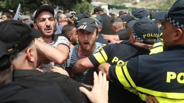 An image showing a group of Georgian men advancing toward a Pride festival in Tbilisi, appearing forceful and determined.