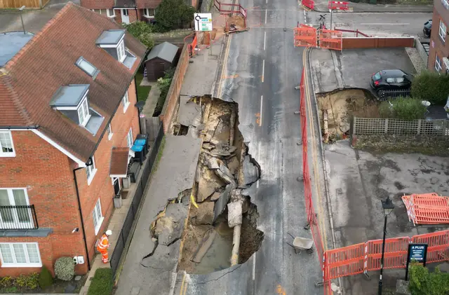 A drone view shows a worker looking towards a large sinkhole in Godstone, southern Britain, February 19, 2025. REUTERS/Toby Melville