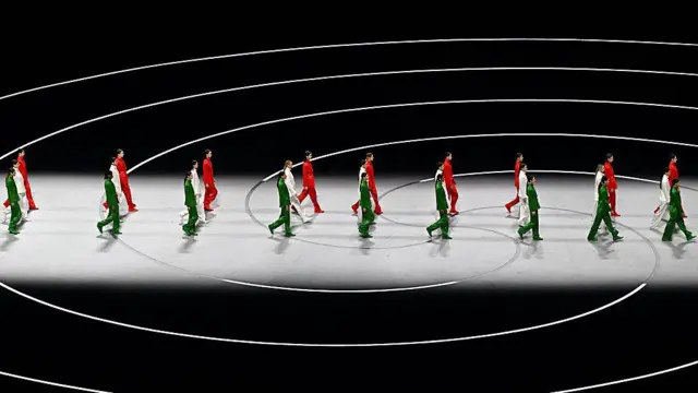 Модели одетые в цвета итальянского флага идут по сцене на открытии Олимпиады 2026.