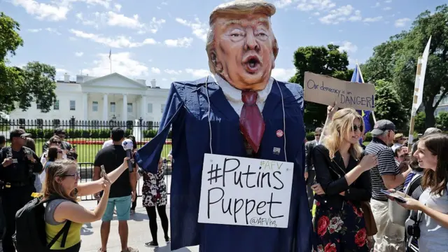 участники демонстрации держат надувную фигуру Трампа