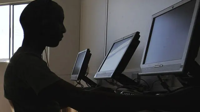 ኮምፒውተር ላይ የተቀመጠ ሰው