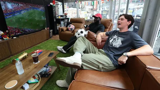 Kevin Akoto y Austin Franklin en la cabina desde la que verán los 104 partidos del Mundial en el Times Square de Nueva York
