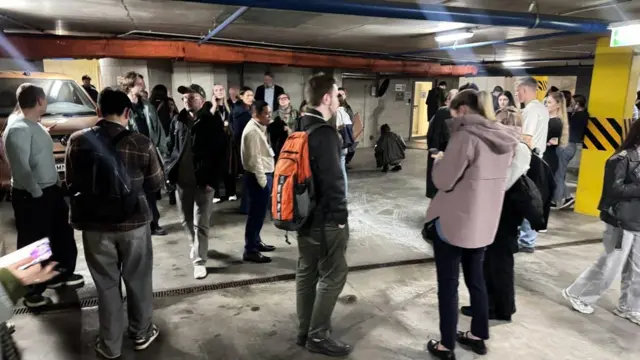 Люди толспятся на подземной парковке