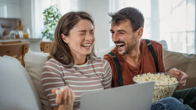 Пара проводить разом спокійний вечір, відпочиваючи на дивані з ноутбуком і мискою попкорну. Насолоджуючись улюбленим фільмом, вони діляться тихими, затишними моментами, занурившись у просте задоволення від спілкування один з одним.