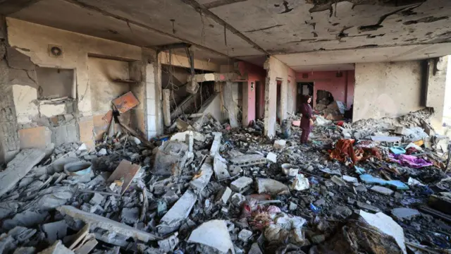 Uma mulher palestina inspeciona os danos a um edifício após um ataque israelense à cidade de Hamad, em Khan Yunis, em 18 de novembro de 2023