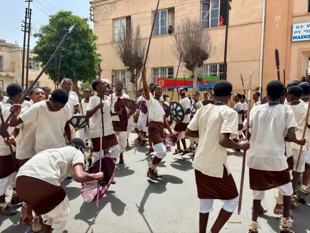 ባህላዊ ልብሲ ዝተኸድኑ፡ ኲናትን ዋልታን ዝሓዙ ኣጓብዝ እናደበሉን እናሳዕስዑን