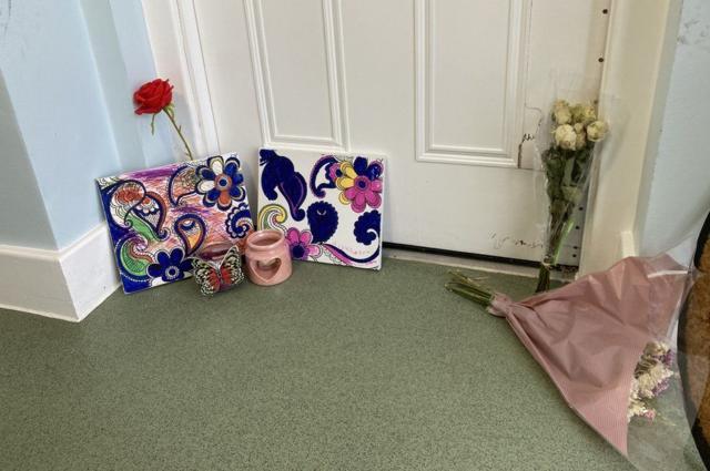 flores e homenagem na frente da porta do apartamentoplataforma de jogos de cassino onlineSheila