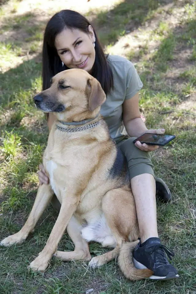 Пас и девојка седе на трави