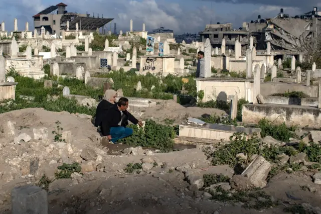 أشخاص يزورون مقبرة في جباليا في غزة