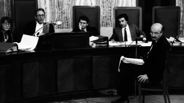 Roberto Calvi duduk di hadapan para hakim dalam persidangan melawannya. Sidang dipimpin oleh hakim Roda Bogetti. Milano, 1980-an.