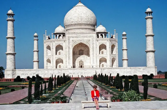 Diana, Princess of Wales, wearing a red and purple suit designed by Catherine Walker, poses alone outside the Taj Mahal on February 11, 1992 in Agra, India. 