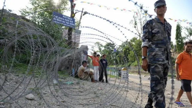 A Nepalese policeman stands guard behind barbed wire on the Indo-Nepal border at Kakrvitta some 46 kms from Siliguri on June 6, 2009