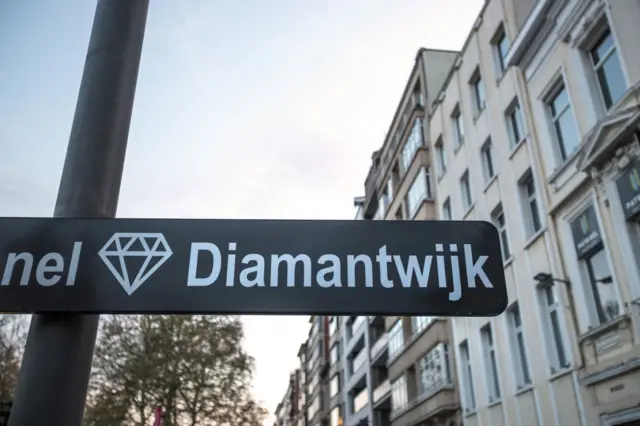 Cartel negro con un ícono de diamante y la palabra ‘Diamantwijk’ en una calle con edificios al fondo.