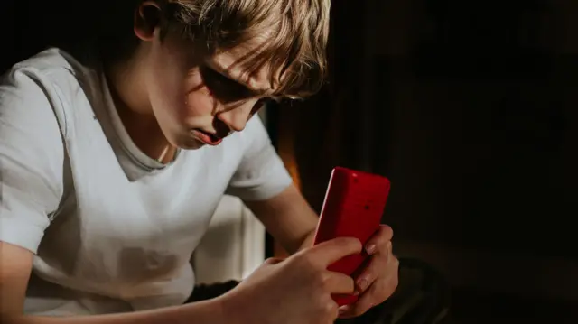 ስልኩን የሚመለከት ታዳጊ