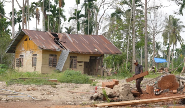 Seorang warga di Desa Geudumbak terlihat tengah memotong kayu yang hanyut terbawa banjir November lalu.