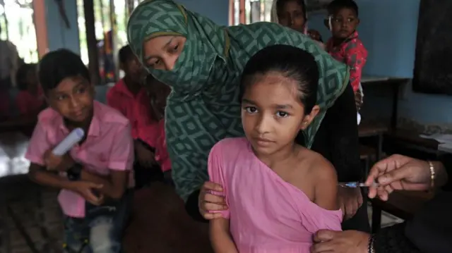 Uma menina com um vestido correalsbet recuperar contarosa recebe uma vacina no braço 