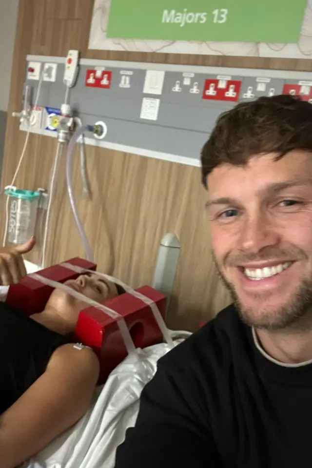 Lauren Macpherson aparece deitada em uma cama de hospital, com dois blocos vermelhos de cada lado da cabeça, ao lado do namorado, Zak. Zak segura a câmera e sorri para a foto. Ele tem cabelo castanho-claro e olhos azuis. Lauren levanta a mão esquerda e faz um gesto de positivo com o polegar