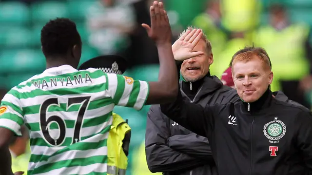 Victor Wanyama, vu de dos, portant un maillot vert et blanc du Celtic avec le numéro 67 dans le dos, s'approche du manager Neil Lennon pour lui faire un high five.