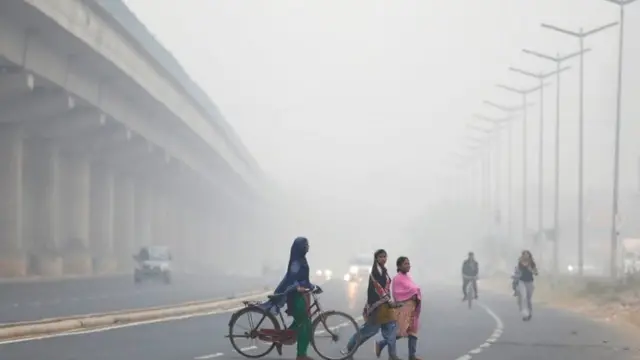 Mujeres cruzan una calle de Nueva Delhi casi sin visibilidad.