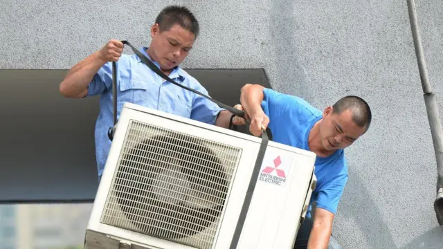 એરકંડિશનરનું કામ કરી રહેલાં કારીગરની તસવીર