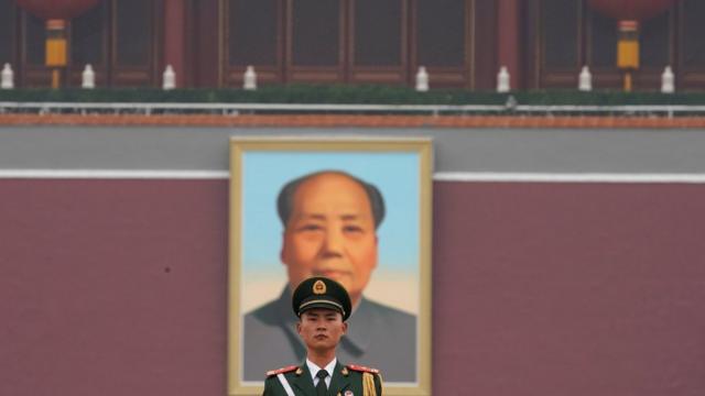 Soldado chino frente al retrato de Mao