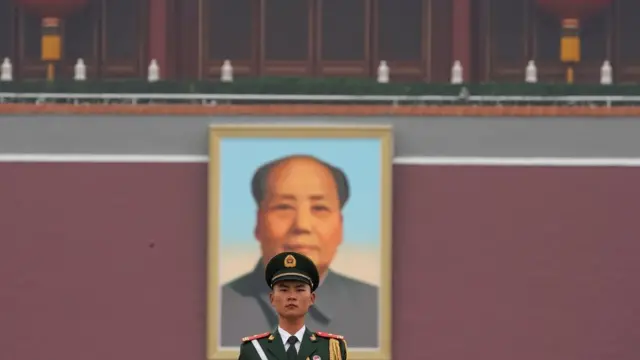 Soldado chino frente al retrato de Mao