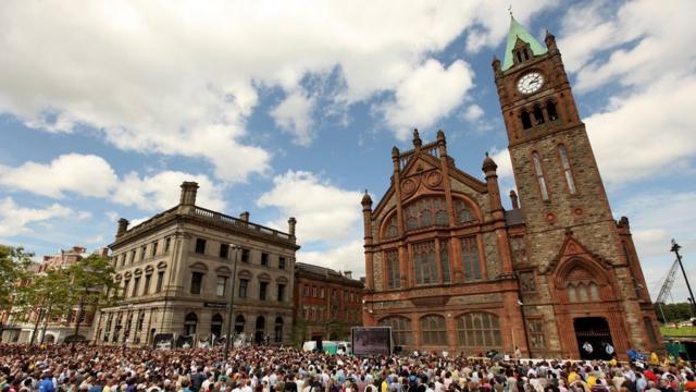 Apoiadores das famílias das vítimas do Domingo Sangrento na Guildhall Square, em Derry, assistindo ao pedido de desculpas do então primeiro-ministro britânico, David Cameron