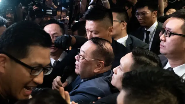 石礼谦在建制派议员护送下进入会议室，泛民主派议员阻止他前往主席台。