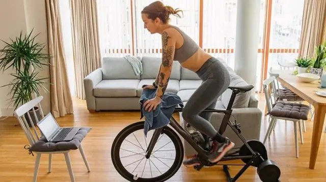 Дівчина займається велотренажері в квартирі