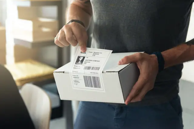 Ilustrasi seseorang menempelkan label barcode di paket.