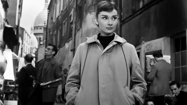 Одрі Гепберн тримає руки в кишенях вільної куртки, чорно-біле фото на вулиці