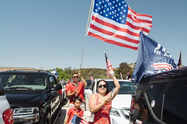 Apoiadores de Trump carregando bandeiras dos EUA em meio a carros