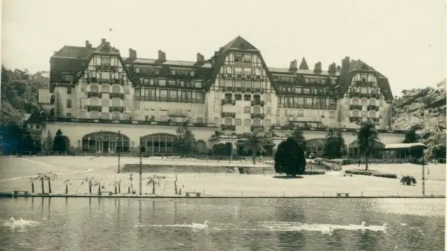 Foto em sépia de um predio grande, parecido a um palácio, na frente de um lago