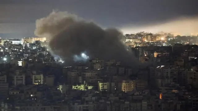 建物が密集する暗い市街地で大きな煙が上がっている