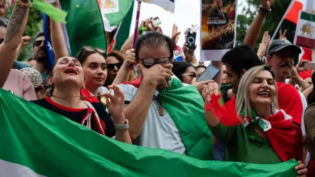 イラン革命前の「獅子と太陽」のイラン国旗を手に、笑ったり泣いたりしている人たち。