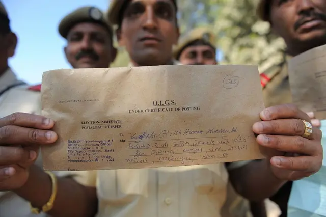 गुजरातमध्ये 2022 च्या निवडणुकीत पोस्टानं मतदान करणारा एक पोलिस कर्मचारी मतदानाचा फॉर्म असलेला लिफाफा दाखवताना.