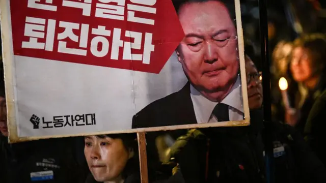 Seorang perempuan memegang plakat bertuliskan "Yoon Suk Yeol harus mundur" dalam demonstrasi Seoul pada tanggal 4 Desember 2024.