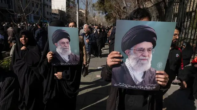 دو شهروند ایرانی در جریان تجمعی در تهران، ایران، در تاریخ ۱ مارس ۲۰۲۶، پس از تایید خبر کشته شدن آیتالله علی خامنهای درتلویزیون دولتی، تصاویر رهبر ایران را در دست گرفتهاند