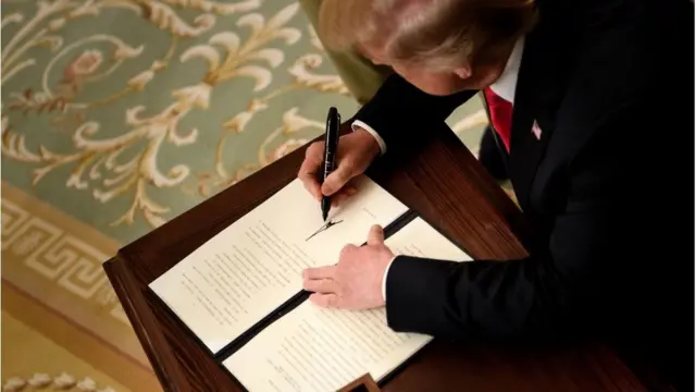 Imagem mostra presidente Donald Trump assinando documento na Casa Branca