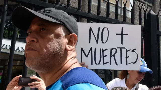 Una persona con un cartel que dice "No más muertes".