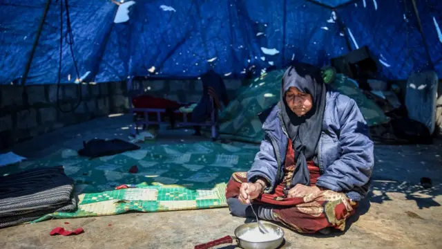 Di kota Idlib, Suriah, seorang ibu terlihat sedang makan di depan tenda pengungsian menjelang bulan suci Ramadan, Selasa (21/03).