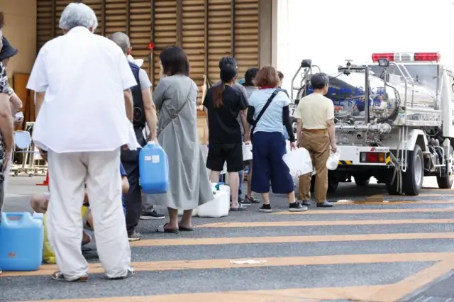 ポリタンクなどを手にした人たちが、給水車の前に並んでいる