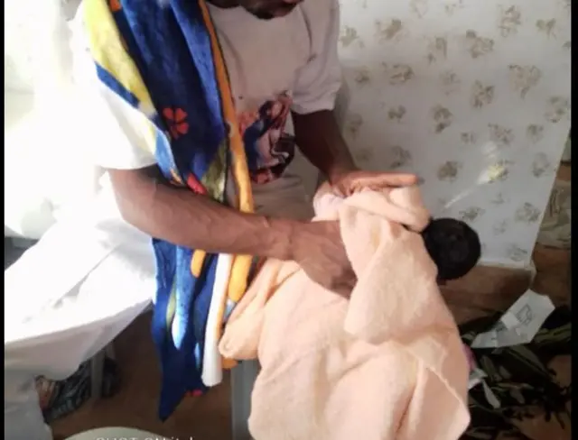 Pasitọ Peter Michonza n wẹ ọmọ tuntun